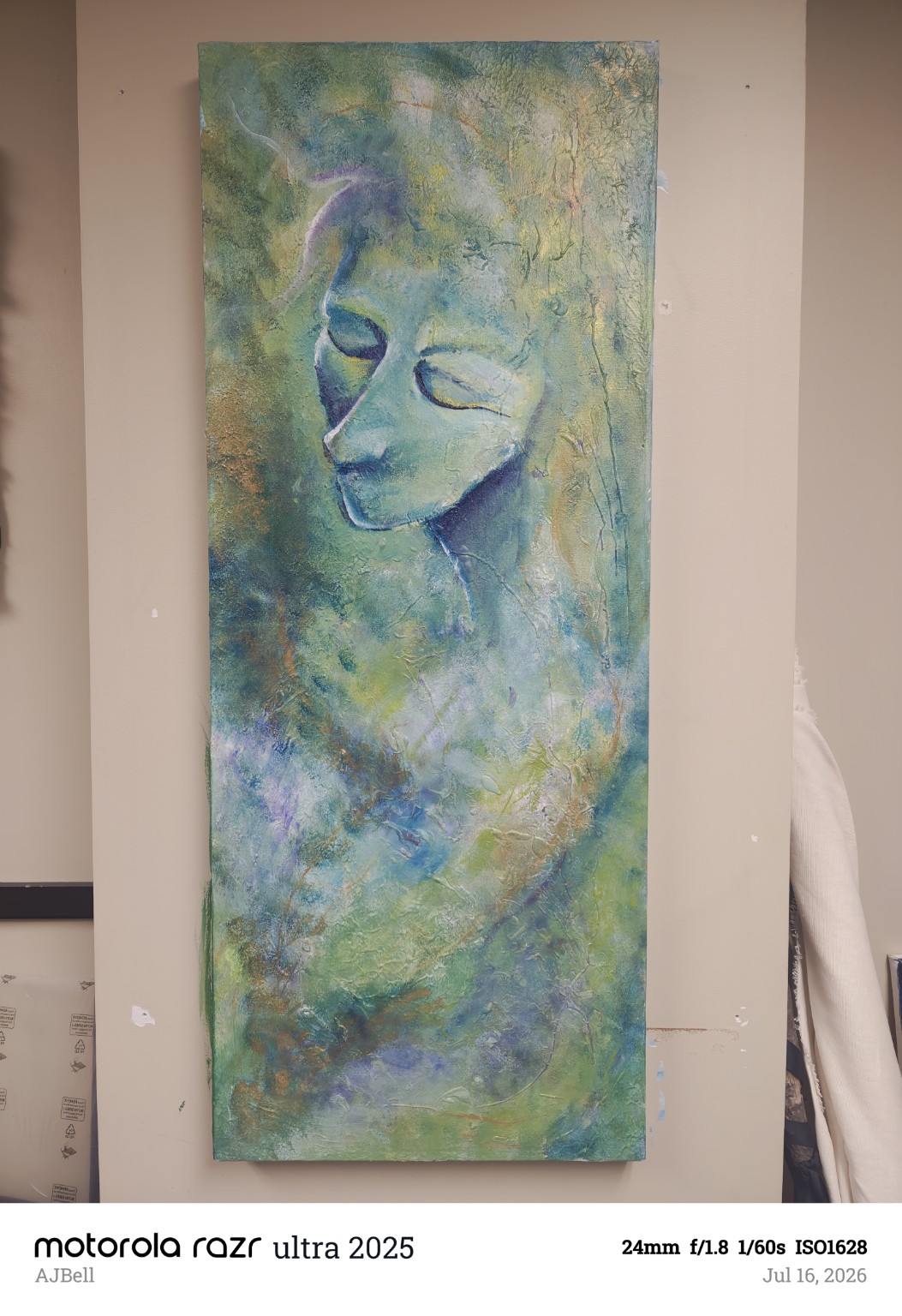 A closed-eye figure emerging from textured green, gold and blue paint